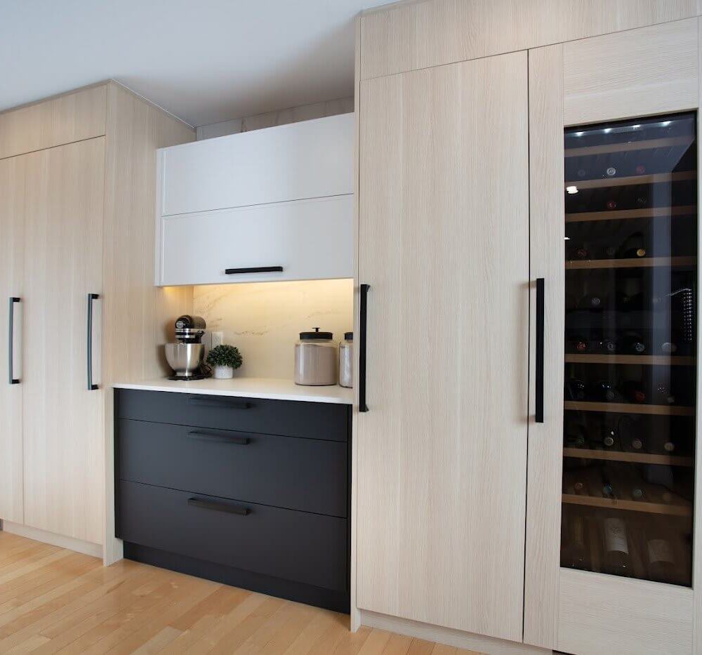 Light oak kitchen cabinetry with black drawers, a built-in wine fridge, and a lit coffee nook in Lakeshore North.