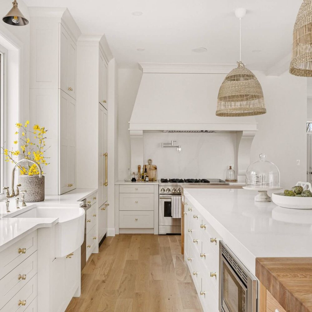 Bright modern kitchen featuring white cabinetry, a large island, and decorative pendant lighting.