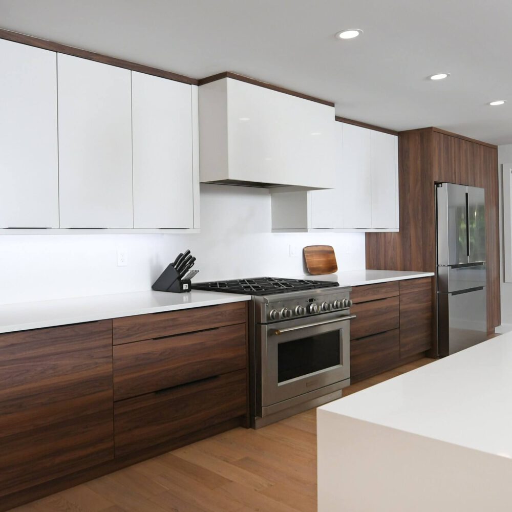 Gaskin modern kitchen by Casey's Kitchens with white upper cabinets, dark wood lower cabinets, stainless steel range, and a bright island centerpiece