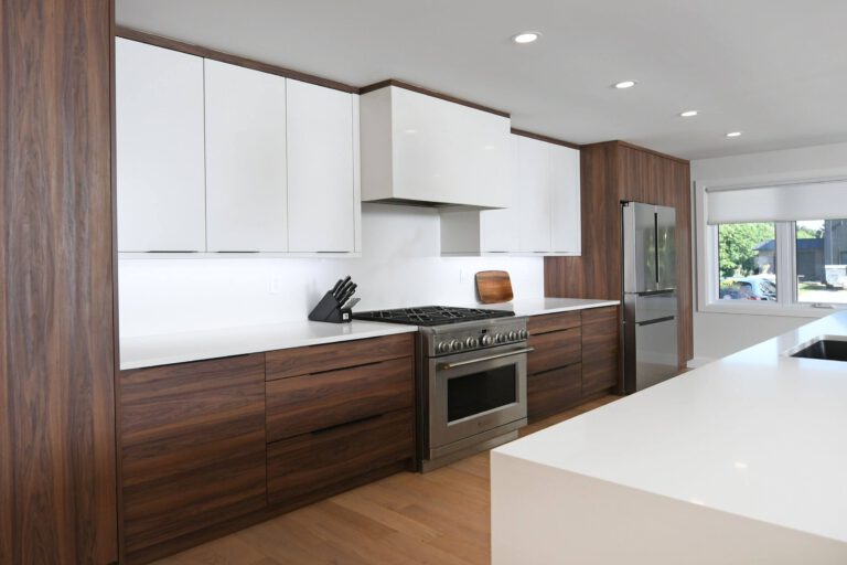 Gaskin modern kitchen by Casey's Kitchens with white upper cabinets, dark wood lower cabinets, stainless steel range, and a bright island centerpiece