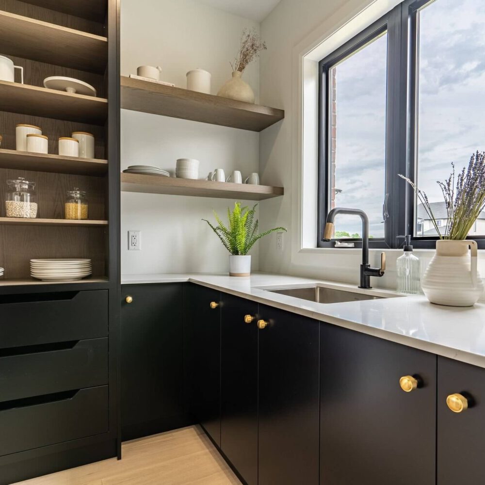 Dark ebony cabinets with oak open shelves, a white countertop, black faucet, and a window above the sink.