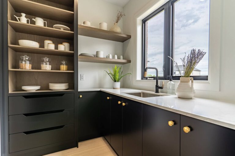 Dark ebony cabinets with oak open shelves, a white countertop, black faucet, and a window above the sink.