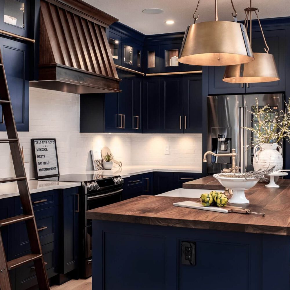 Modern kitchen with navy blue cabinetry, a wooden island, pendant lighting, and a ladder against the wall.