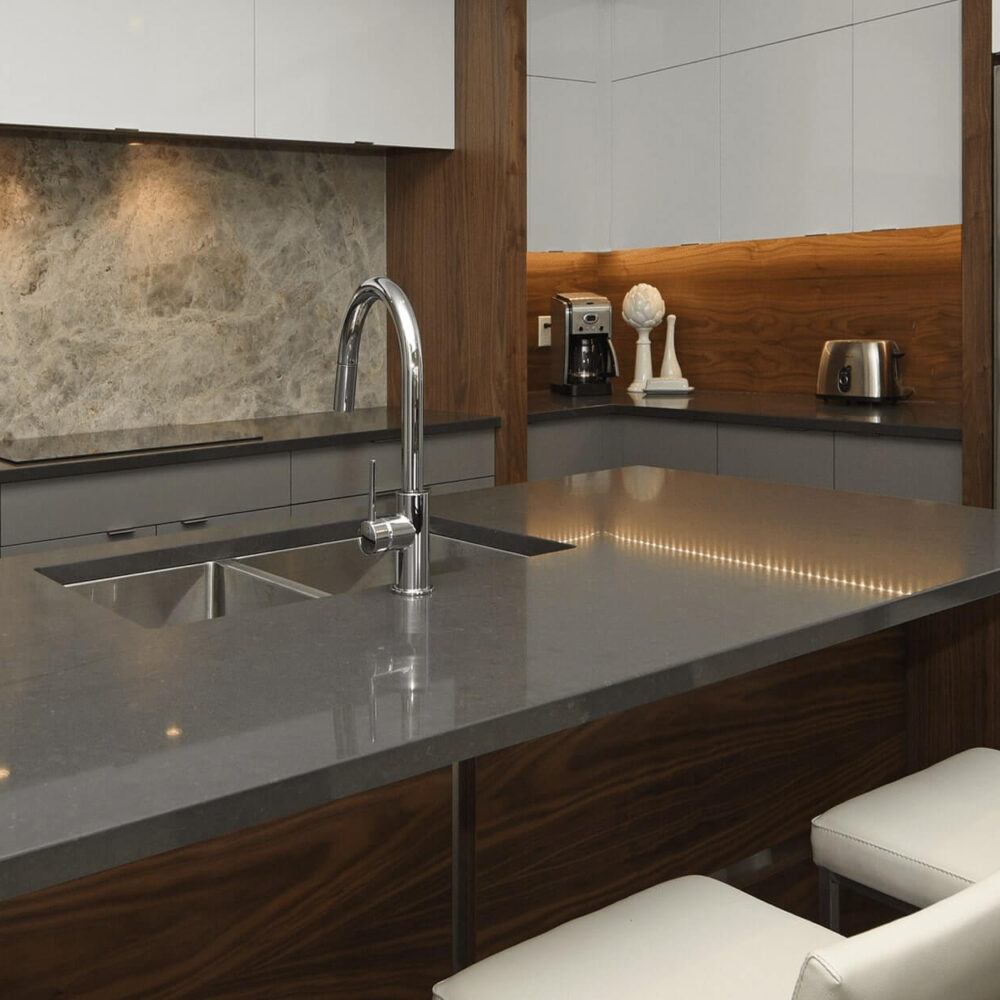 Modern kitchen with a gray countertop, stainless steel appliances, and white cabinetry featuring a sleek design.