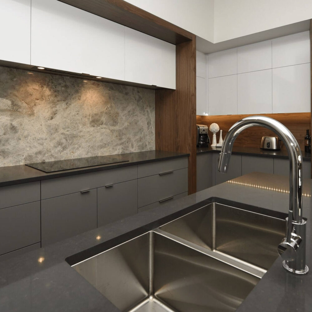 Modern kitchen design featuring sleek gray cabinetry, stainless steel appliances, and a double sink with a polished faucet.
