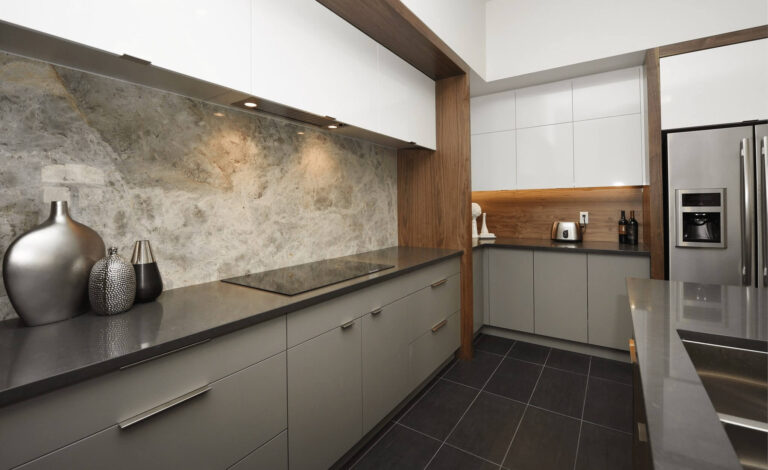 Modern kitchen design featuring sleek gray cabinetry, a stone backsplash, and stainless steel appliances.
