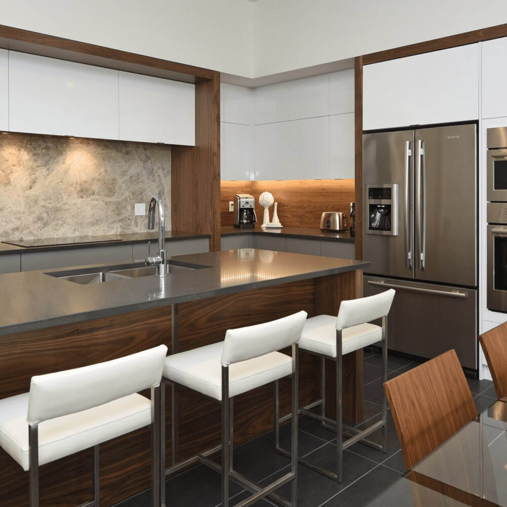 Callingham kitchen by Casey's Kitchens featuring stainless steel Bosch appliances, white upper cabinets, walnut lower cabinetry, and a stone backsplash in a modern open layout.
