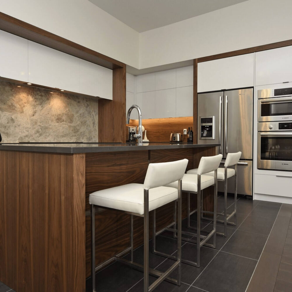 Callingham kitchen by Casey's Kitchens with high-gloss white upper cabinets, warm walnut island and cabinetry, and a marble backsplash, complemented by stainless steel appliances.