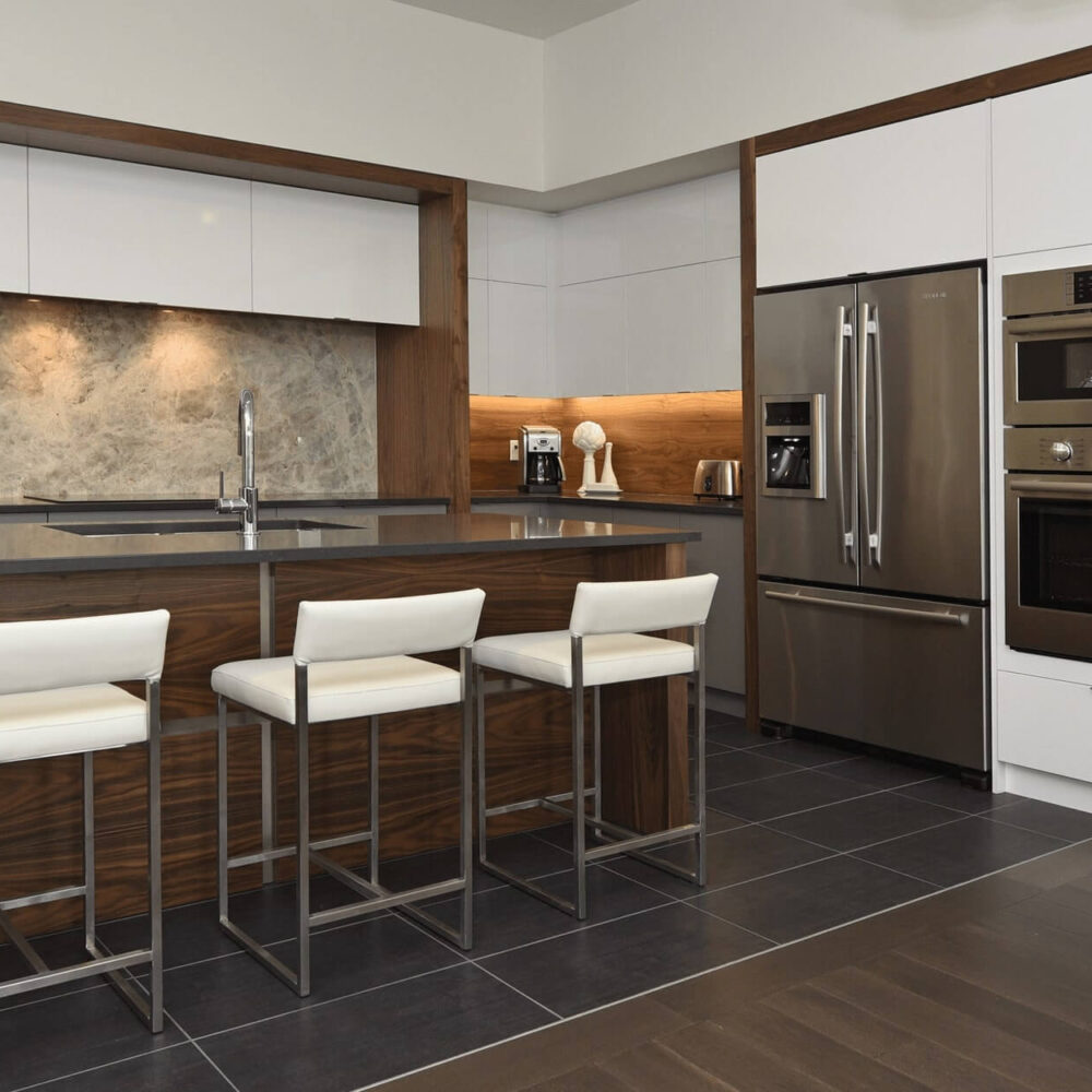 Callingham kitchen by Casey's Kitchens with high-gloss white cabinets, walnut accents, marble backsplash, and stainless steel appliances in a modern London, Ontario space.
