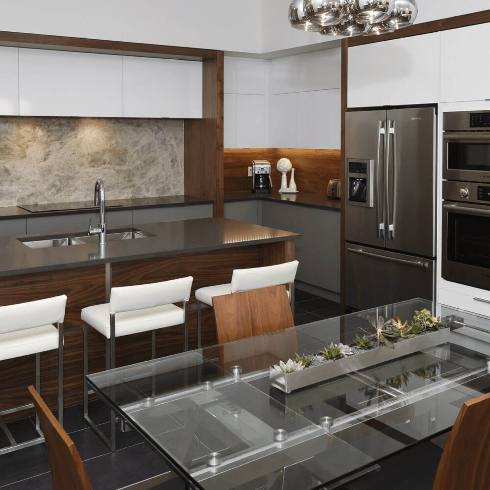 Callingham kitchen by Casey's Kitchens featuring walnut cabinetry with white high-gloss upper cabinets, a dark countertop island, stainless steel refrigerator and double wall ovens, and a marble backsplash.