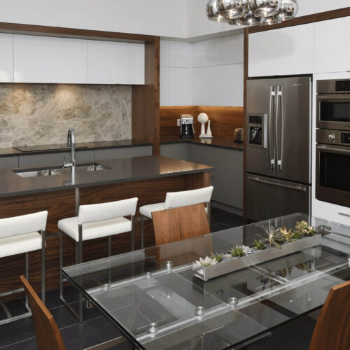 Callingham kitchen by Casey's Kitchens featuring walnut cabinetry with white high-gloss upper cabinets, a dark countertop island, stainless steel refrigerator and double wall ovens, and a marble backsplash.