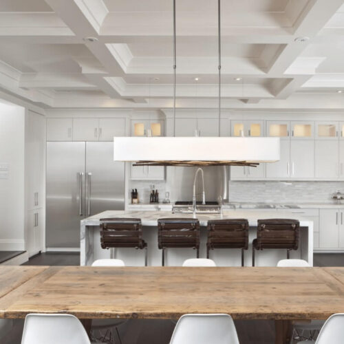 Modern kitchen with white cabinetry, stainless steel appliances, and a wooden dining table with white chairs.