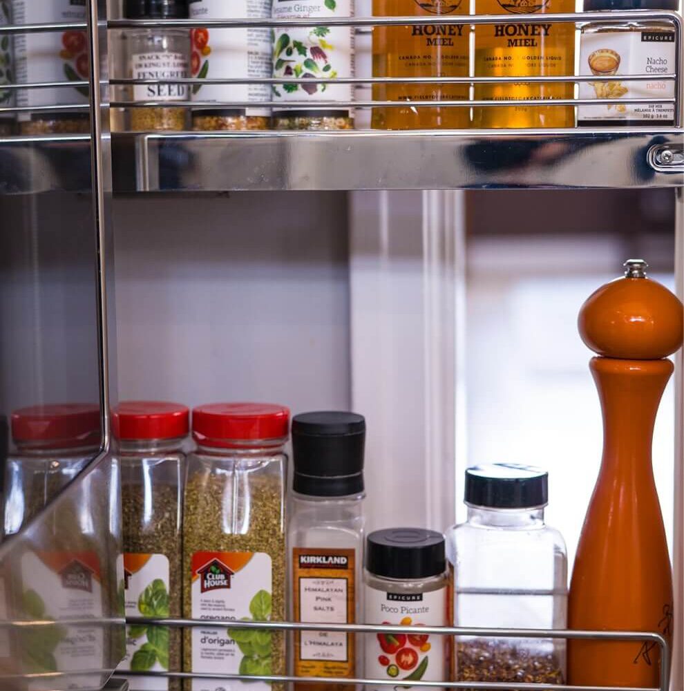 Old South Kitchen by Casey's Kitchens with spice jars, honey jars labeled Field To Fork, and a tall orange pepper mill on a chrome pull-out rack in a compact 75 sq ft space