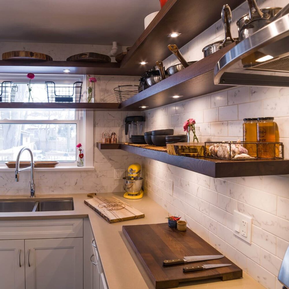 Old South Kitchen project by Casey's Kitchens featuring white cabinetry, a white subway-tiled backsplash, and walnut floating shelves with a stainless steel sink, bright window light, and a yellow mixer