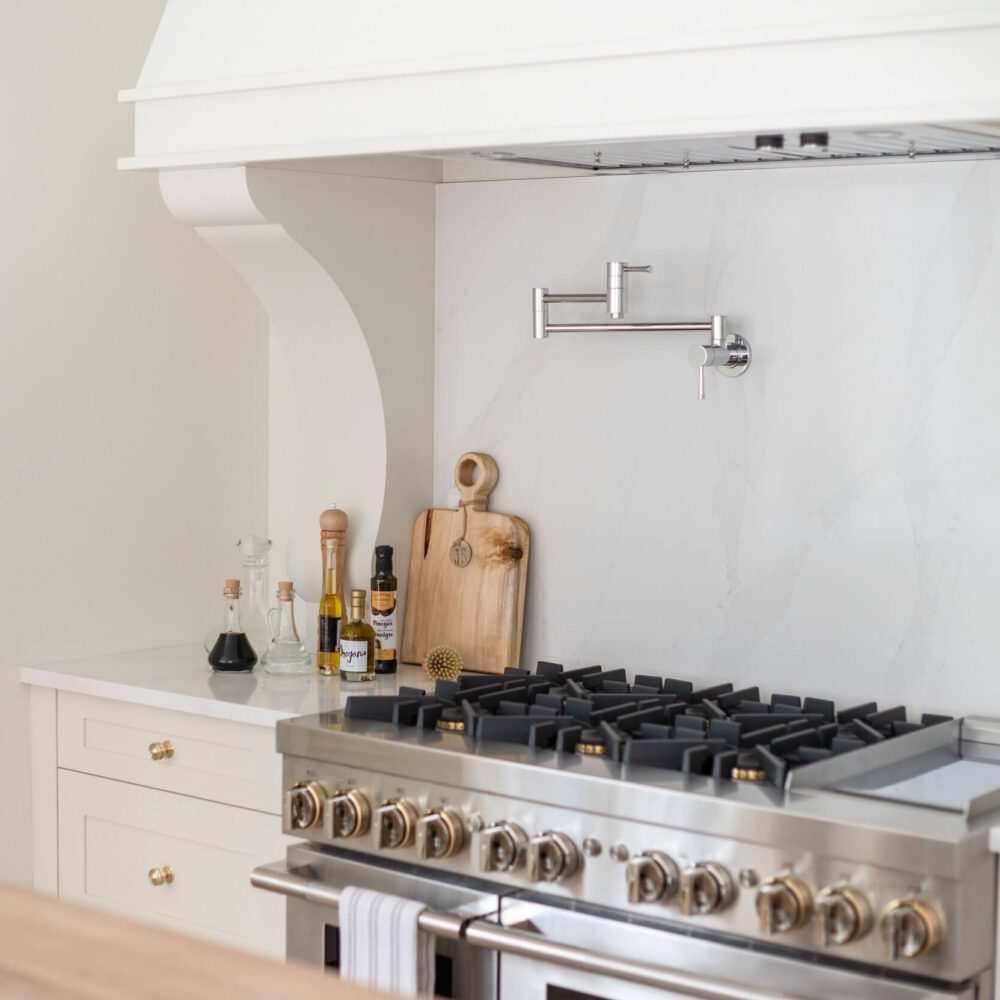 Stainless steel stove with a marble backsplash and wooden cutting board in a modern kitchen.