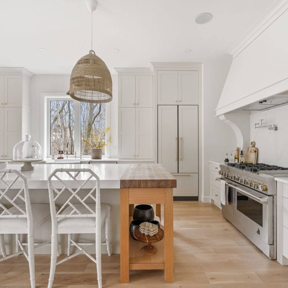Bright modern kitchen featuring white cabinetry, a wooden island, and pendant lighting.