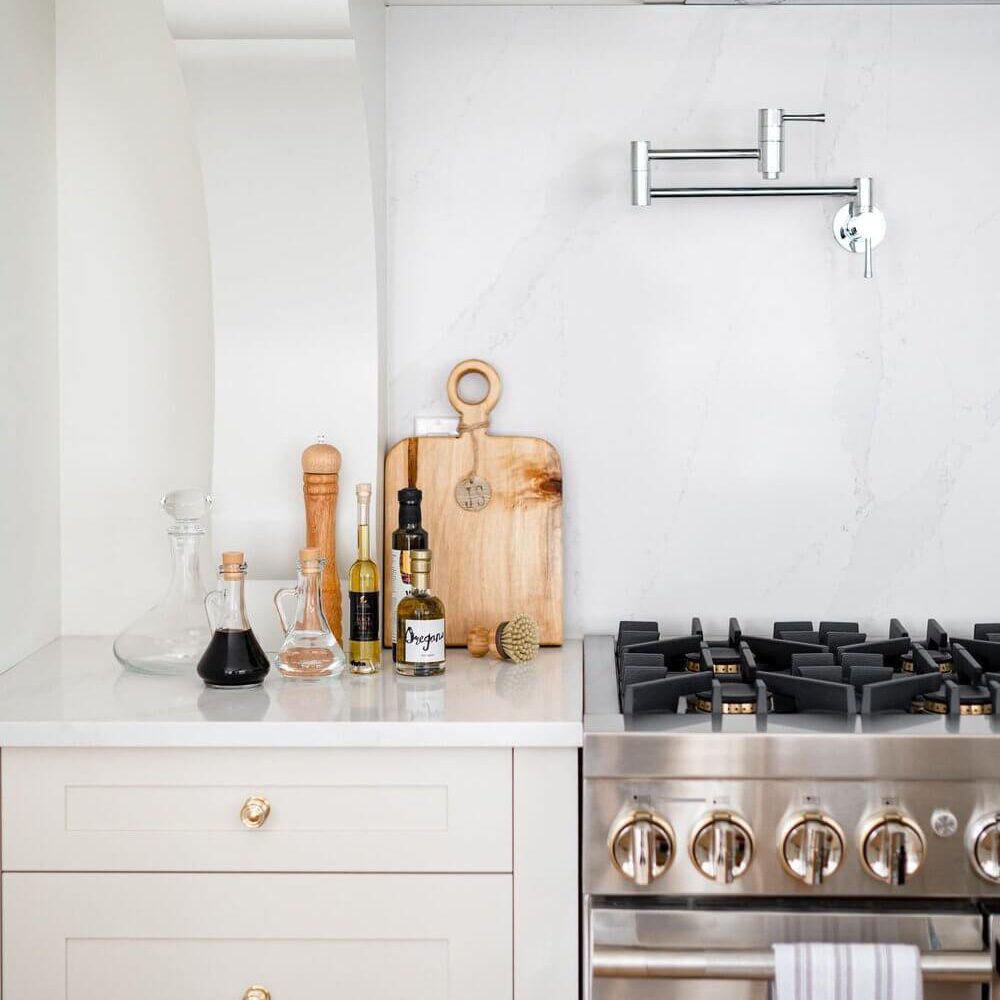 Kitchen counter featuring a stainless steel stove, cutting board, and various cooking oils and utensils.