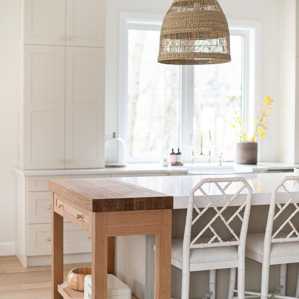 Contemporary kitchen featuring a wooden island and a rattan pendant light above a dining area.
