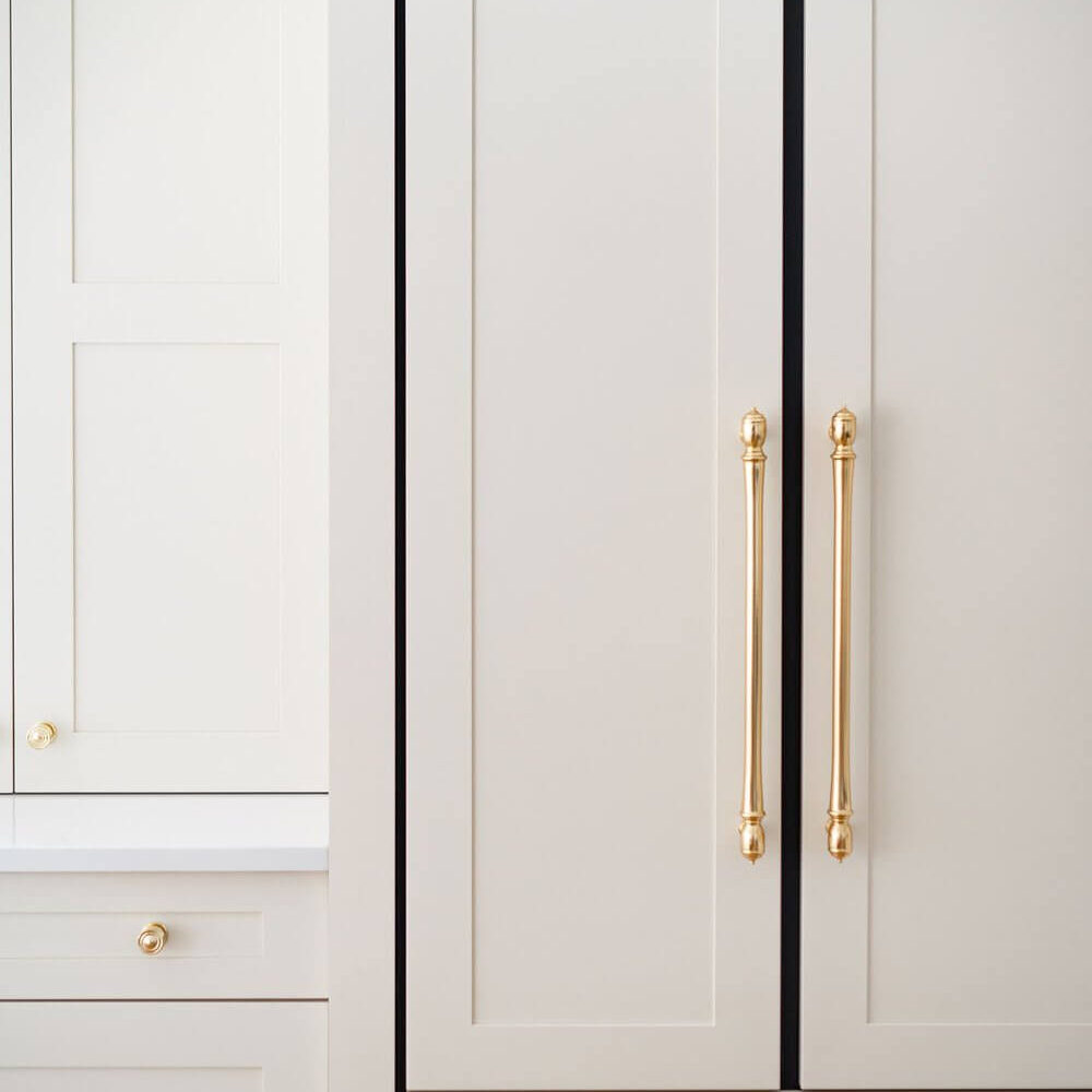 A modern kitchen refrigerator with a sleek design and gold handles, featuring a light grey finish.