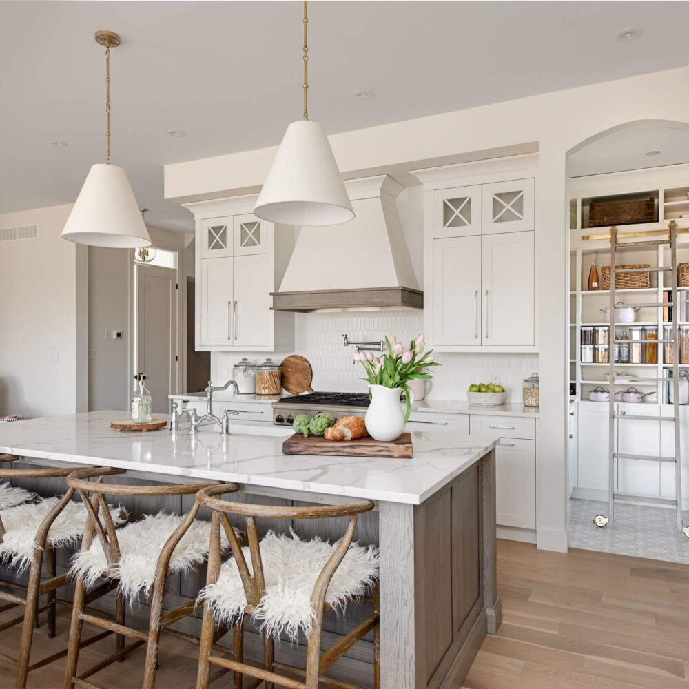 Byron Beauty kitchen by Casey's Kitchens with muted white cabinetry, oak accents, a marble island, and brass hardware in a modern French Country style, located in London, Ontario