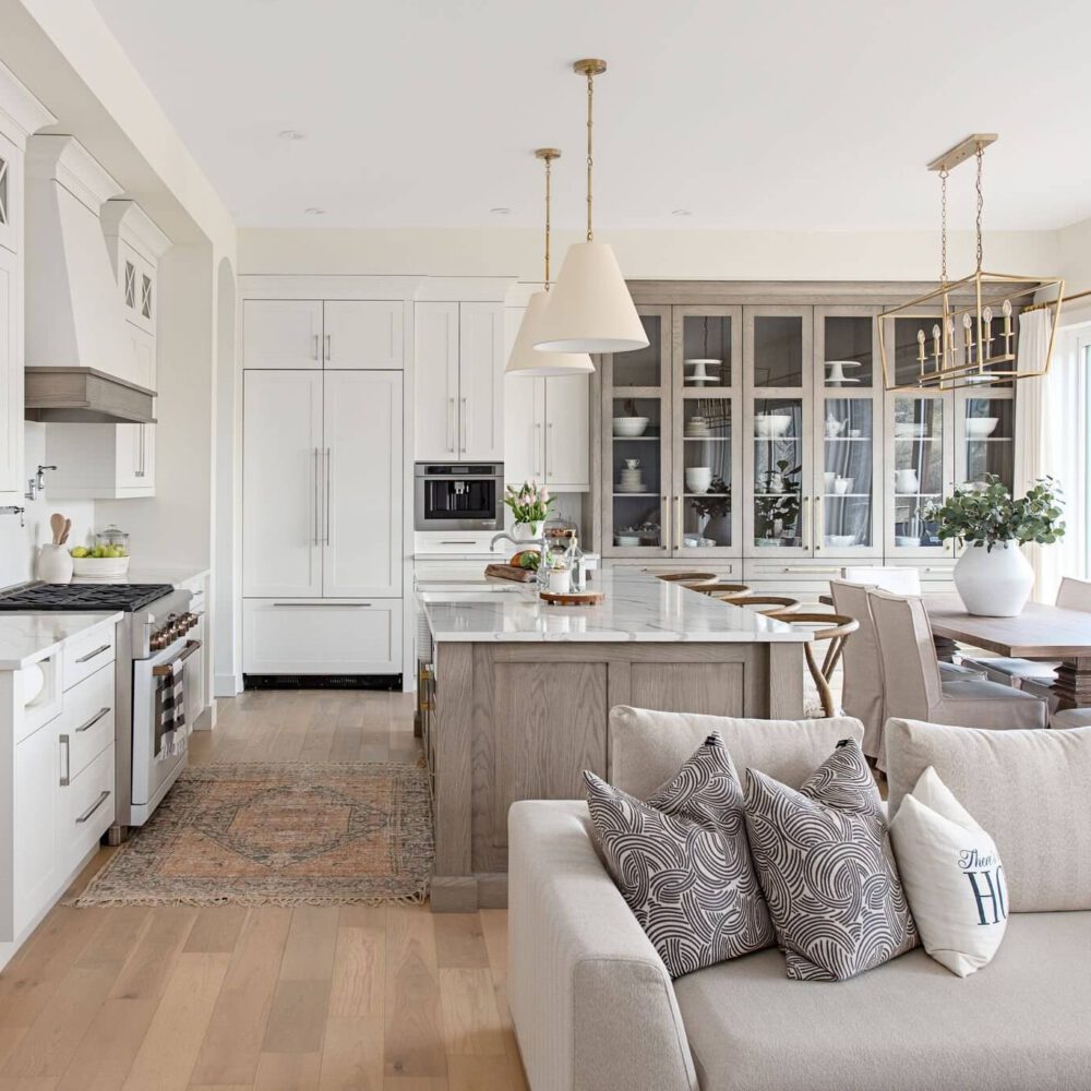 Bright white kitchen with a central island, white cabinetry, glass-front hutch, and a dining area, from Byron Beauty by Casey's Kitchens in London, Ontario.
