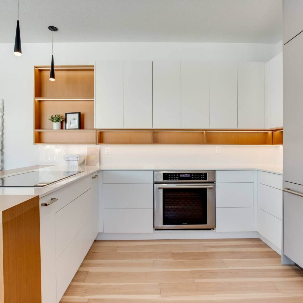 Modern kitchen design featuring white cabinetry, wooden accents, and stainless steel appliances with a clean, minimalist aesthetic.