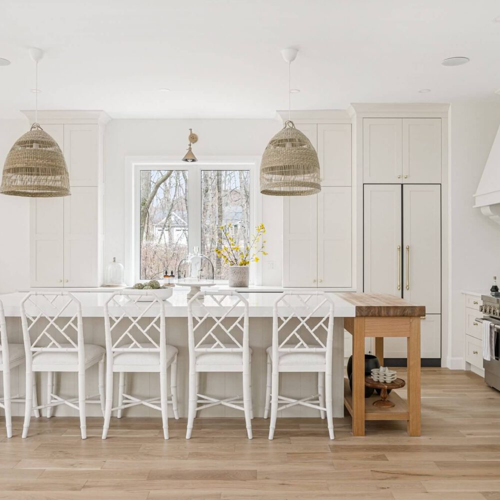 Modern kitchen featuring white bar stools, pendant lights, and a large island with a wooden countertop.