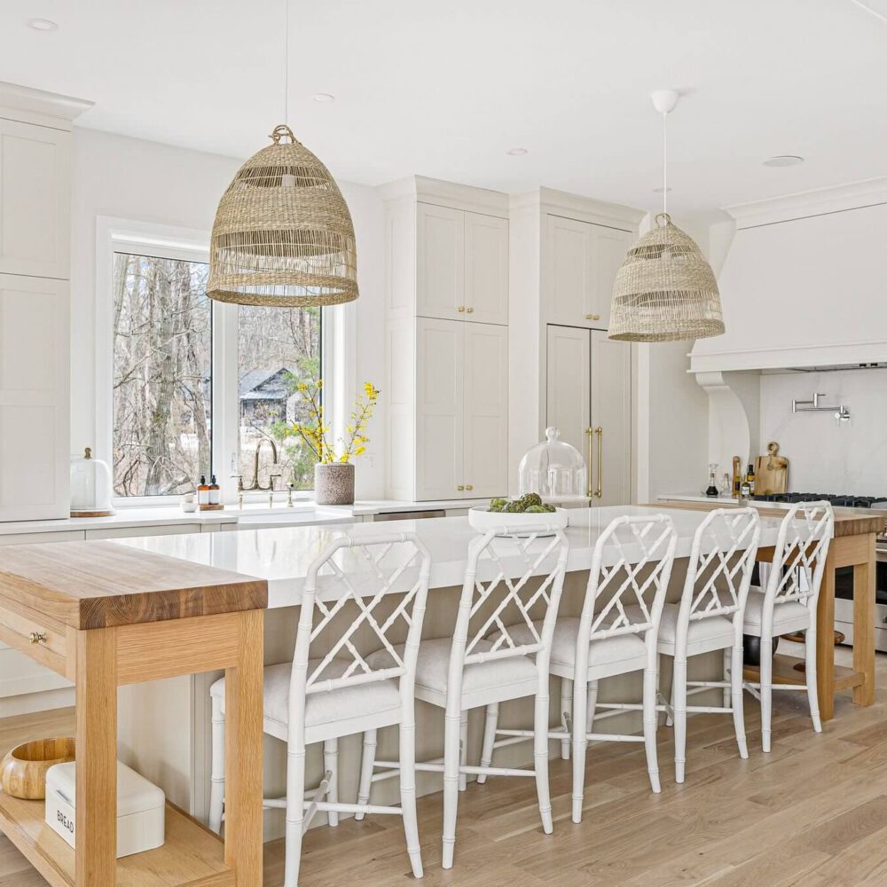 Bright modern kitchen featuring white cabinets, a large island, and woven pendant lights.